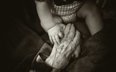 an older woman holding a baby's hand